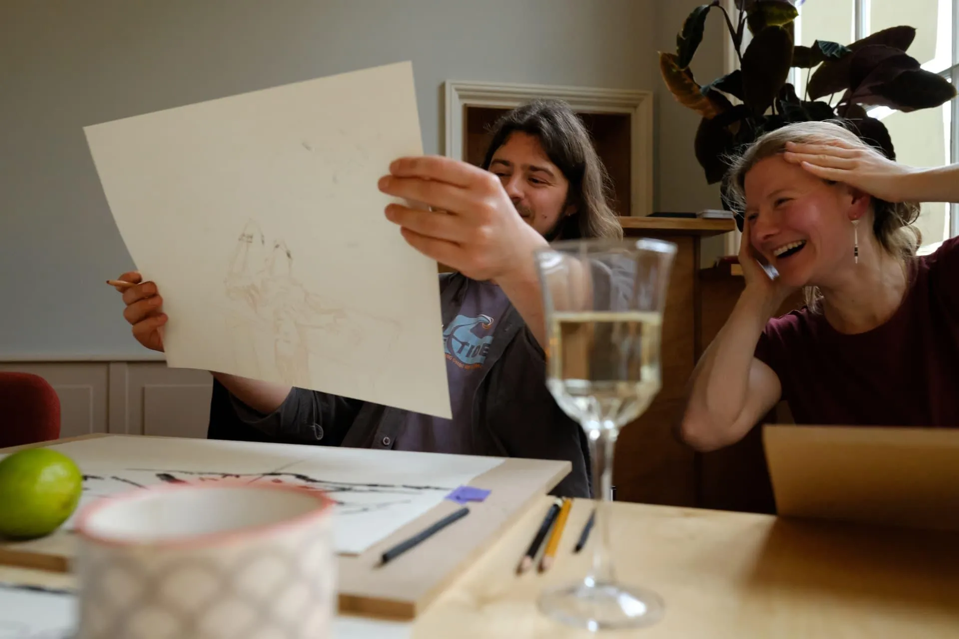 Two participants laughing while holding up a drawing made in the workshop